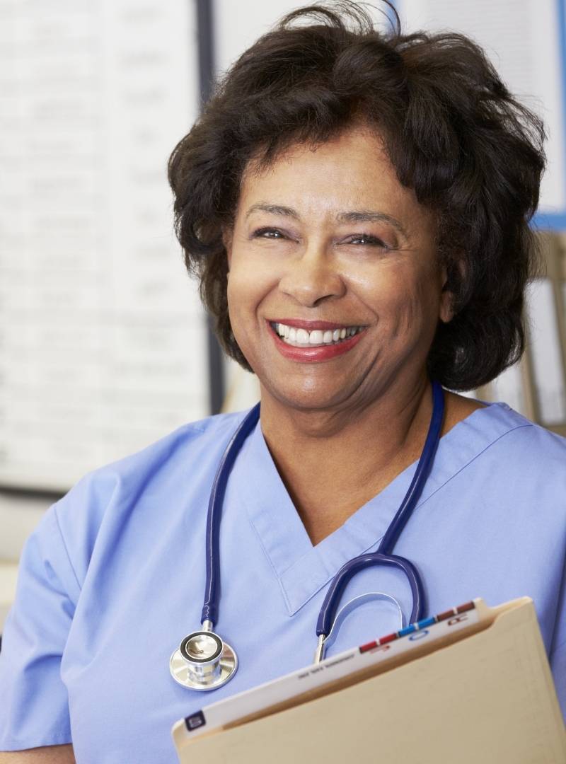 Older nurse smiling with clipboard